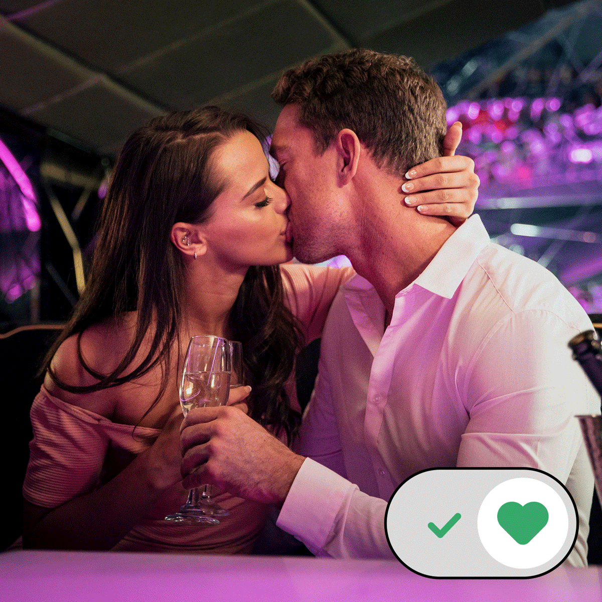 A couple kisses at a table in a dimly lit, colorful restaurant; a wine glass is held by one person.