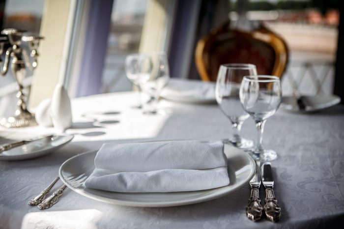 Served table on the ship. Serving of the dinner table in the cabin restaurant ocean liner. Food and service at the marine ship. Utensils for passenger cruises.