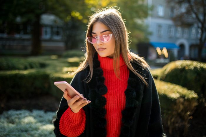 Happy woman walking and writing or reading sms messages on line on a smart phone