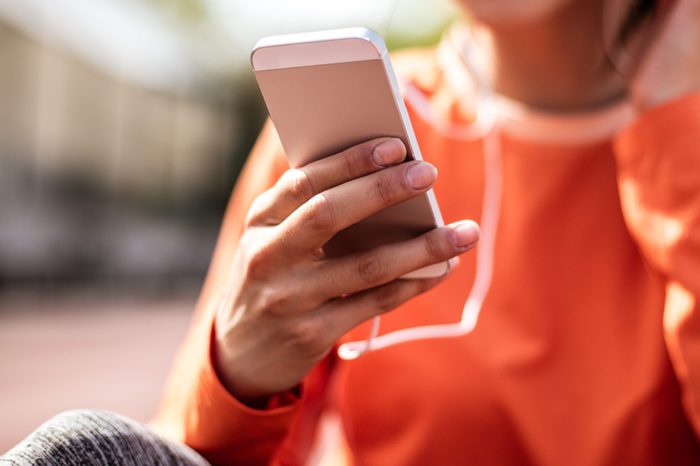 Music for relax. Close up image sport woman using smart phone. Focus on hand.