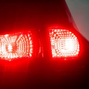 Car taillight glowing brightly, illuminating in the dark environment as the car is stationary.