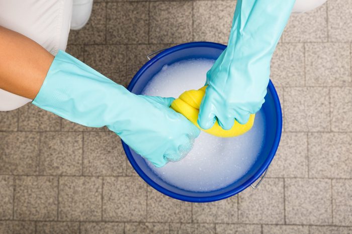 Close-up Of Cleaner Woman Hand Squeezing Cloth In Bucket Filled With Soap Sud