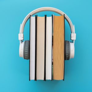 Headphones rest on four upright books, set against a plain blue background.