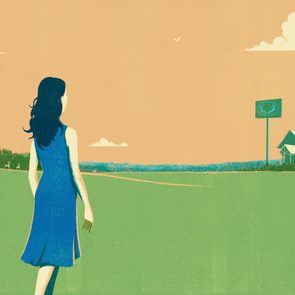 A woman walks across a grassy field toward a distant barn and sign with antlers, under a cloudy sky with birds.