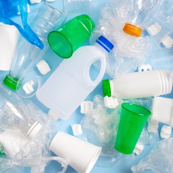 Plastic waste, including bottles, cups, and bags, scattered on a blue background.