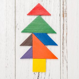 Colored geometric shapes form a tree on a white wooden background.