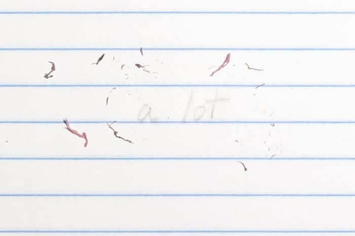 erased text "a lot" with eraser shavings on loose leaf paper