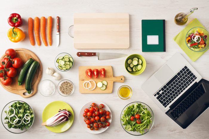 Vegetarian creative cooking at home with kitchen utensils, food ingredients and fresh vegetables on a wooden table, top view