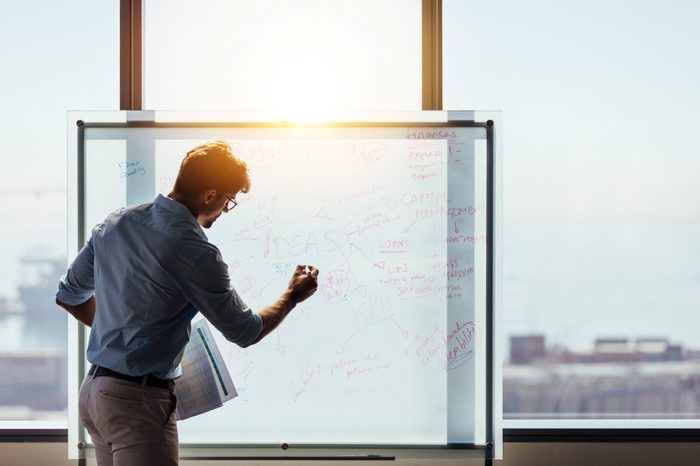 Businessman making a presentation at office. Entrepreneur using whiteboard to present ideas for business planning and decision making.