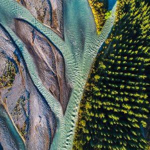 River flows between rocky terrain and dense forest, viewed from above.