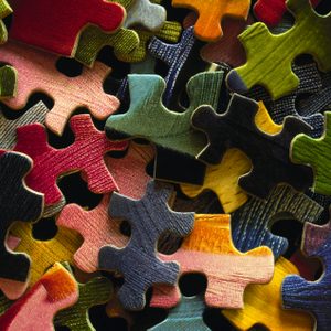 Puzzle pieces scattered randomly, overlapping in various directions, displaying diverse colors and textures against each other.