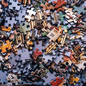 Puzzle pieces lie jumbled, featuring colorful, irregular shapes in an intertwined, chaotic pattern.