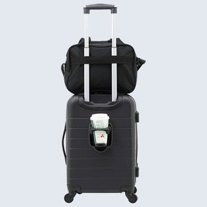 Black suitcase holds a coffee cup, topped with a small black bag, set against a plain background.