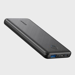 A sleek black portable charger lies at an angle against a plain background, displaying USB ports and a power indicator.
