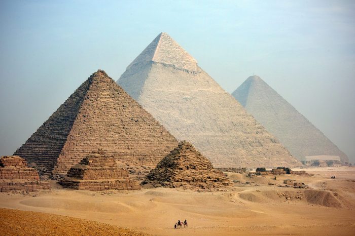A distant camel caravan passes the majestic pyramids at Giza in Cairo at dusk. Egypt