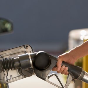 A gas nozzle inserted into a car's fuel tank, being held by a person at a gas station.