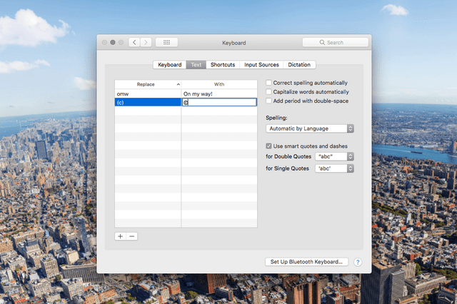 A computer screen shows keyboard text shortcuts settings, displaying "omw" to "On my way!" against a city aerial view background.