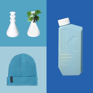 White vases with greenery complement a blue beanie and shampoo bottle labeled 