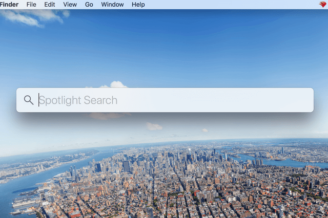 Spotlight Search bar hovers over an aerial view of a sprawling cityscape with rivers and skyscrapers under a clear blue sky.