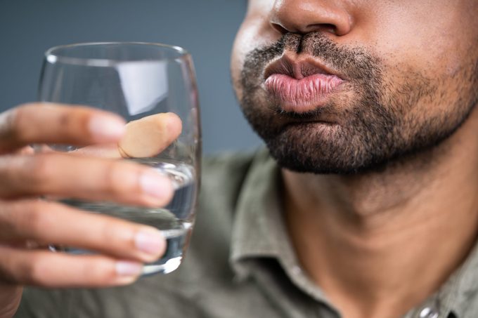 Man Rinsing And Gargling With Water In Glass