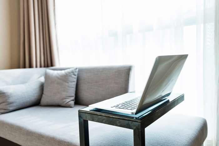 Laptop on table near gray sofa