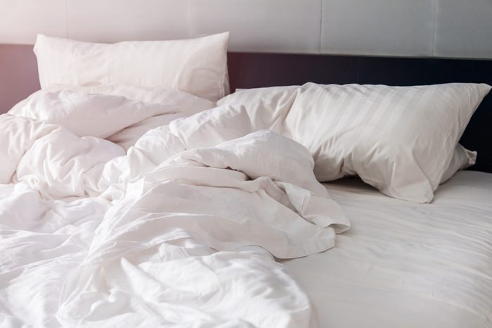 bed and white pillows with wrinkle blanket in bedroom