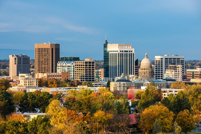 Buildings stand tall under a clear sky, surrounded by autumnal trees in a cityscape.