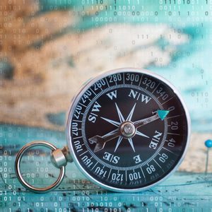 A compass lies on a teal surface, surrounded by faint binary code in the blurred background, suggesting a digital theme.