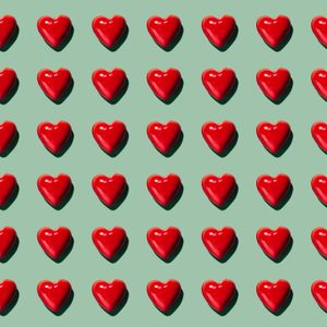 Red hearts arranged in a neat, symmetrical grid on a light green background, casting subtle shadows.