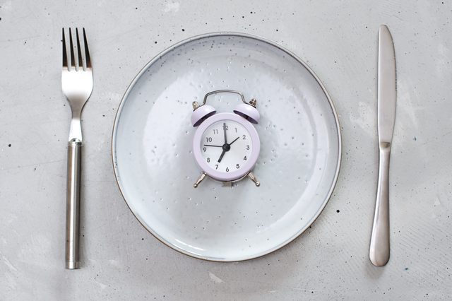 breakfast time concept with alarm clock plate, fork, knife, spoon,