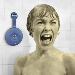 Round blue speaker with water droplets attached to a shower wall; a person is visibly screaming in the tiled bathroom.