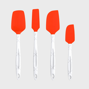 Four silicone spatulas with red blades and white handles, hanging against a plain gray background.
