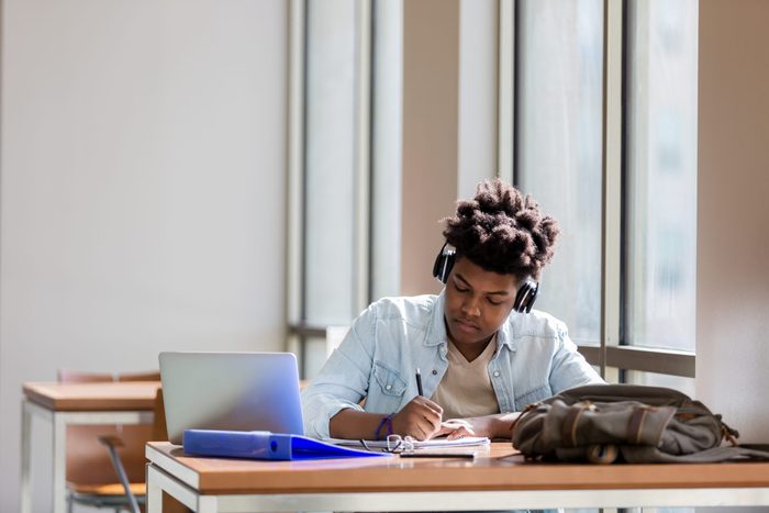 Male high school student studies in campus library