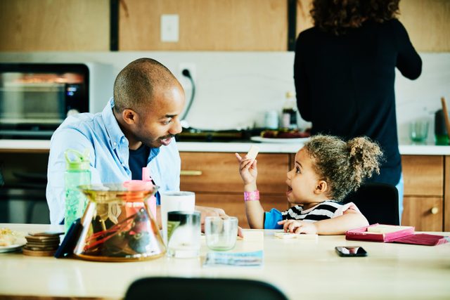 Young girl playing game with father at kitchen table