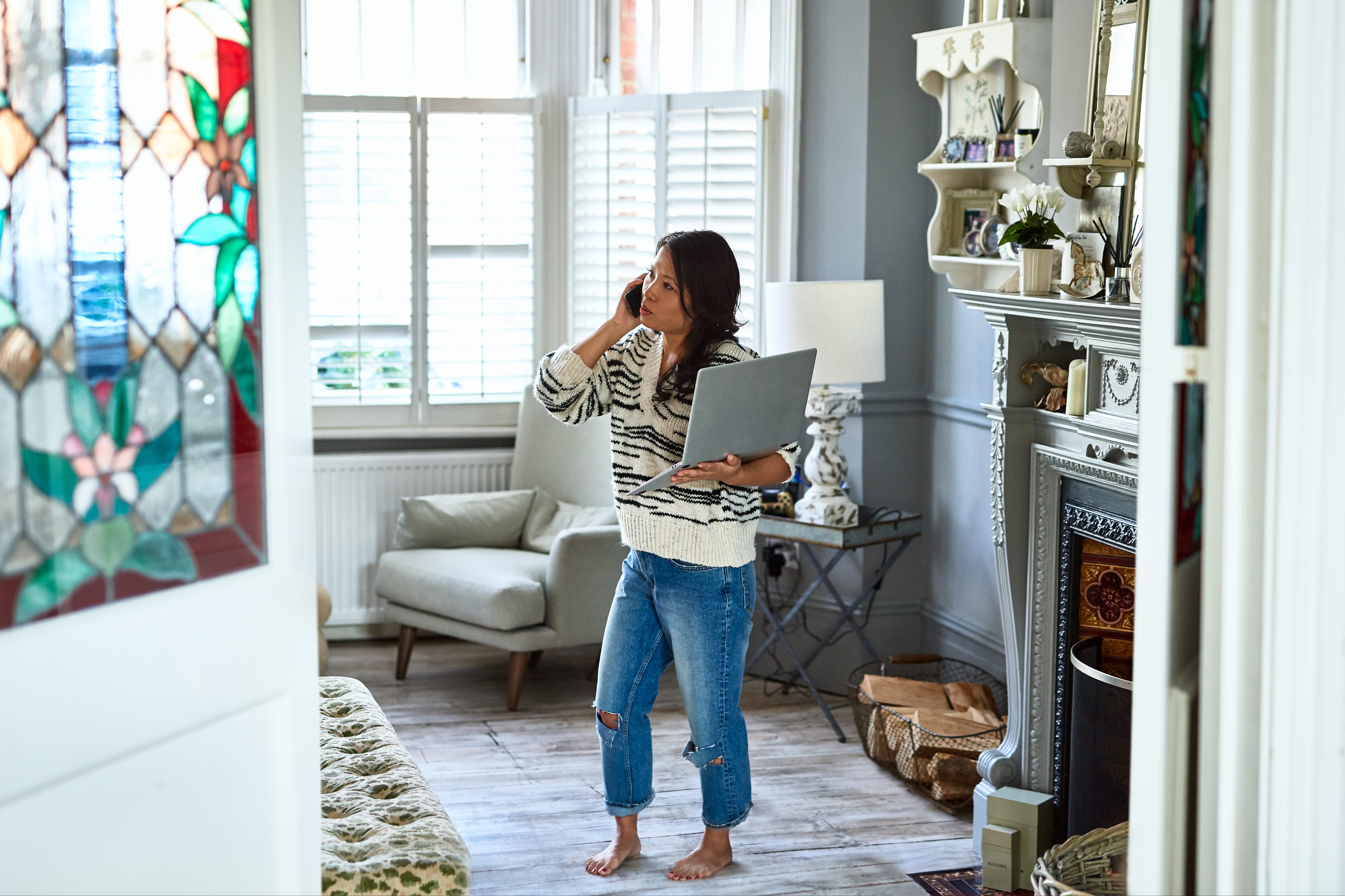 Concerned woman in her 30s on phone with laptop