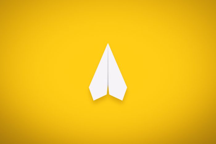 A Single Paper Airplane on Yellow Background