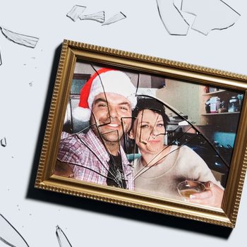 A broken photo frame lies scattered, showing a smiling couple; one wearing a Santa hat, in a cozy home setting with kitchen shelves visible.
