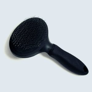 A black hairbrush lies horizontally on a light background, featuring dense bristles and an ergonomic handle with a hanging hole.