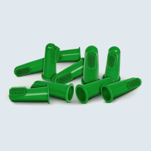 Silicone finger toothbrushes lie scattered on a flat surface, featuring green bristles atop each piece, in a plain, light-colored background.