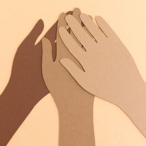 Cutout paper hands overlap gently, layered on a light beige background.