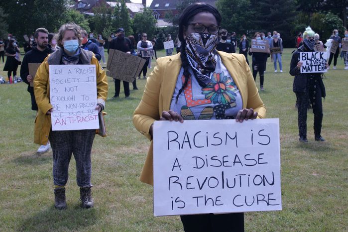 Protesters wearing face masks hold placards during the...