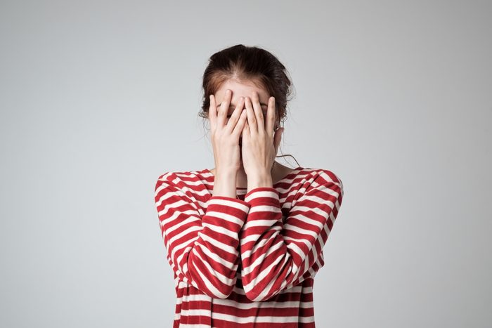 Pretty caucasian girl covers her face with her hands