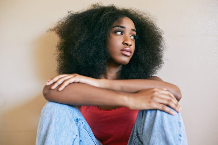 Mixed race woman sitting with arms crossed