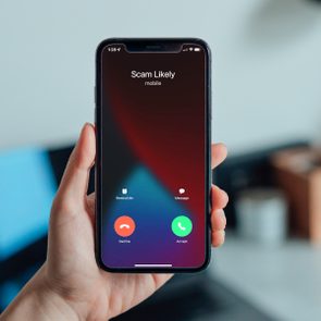 Hand holds smartphone displaying incoming call labeled 