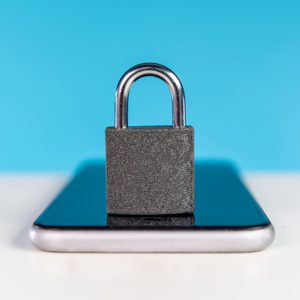 A padlock sits on a smartphone, illustrating security, with a bright blue background.