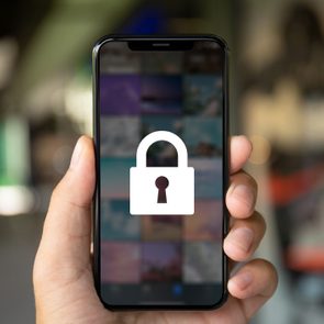 Smartphone screen displaying lock icon, held in a hand, with blurred background.