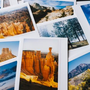 Photographs display stunning landscapes, featuring rock formations and forests, scattered on a surface. A signpost with multiple signs appears in one photo.