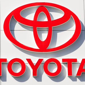 Red Toyota logo displaying prominently on a white tiled wall. The text 