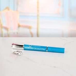 Blue cleaning stick and ring sitting on a marble surface in a softly blurred, elegant room.