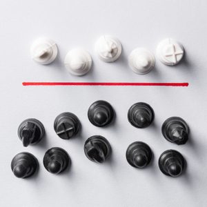 White and black chess pieces arranged on paper, divided by a horizontal red line, creating contrasting groups.